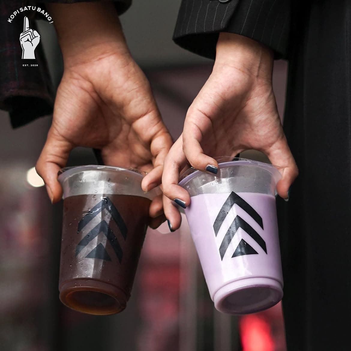 Dua orang memegang dua minuman Kopi Satu Bang bersama-sama