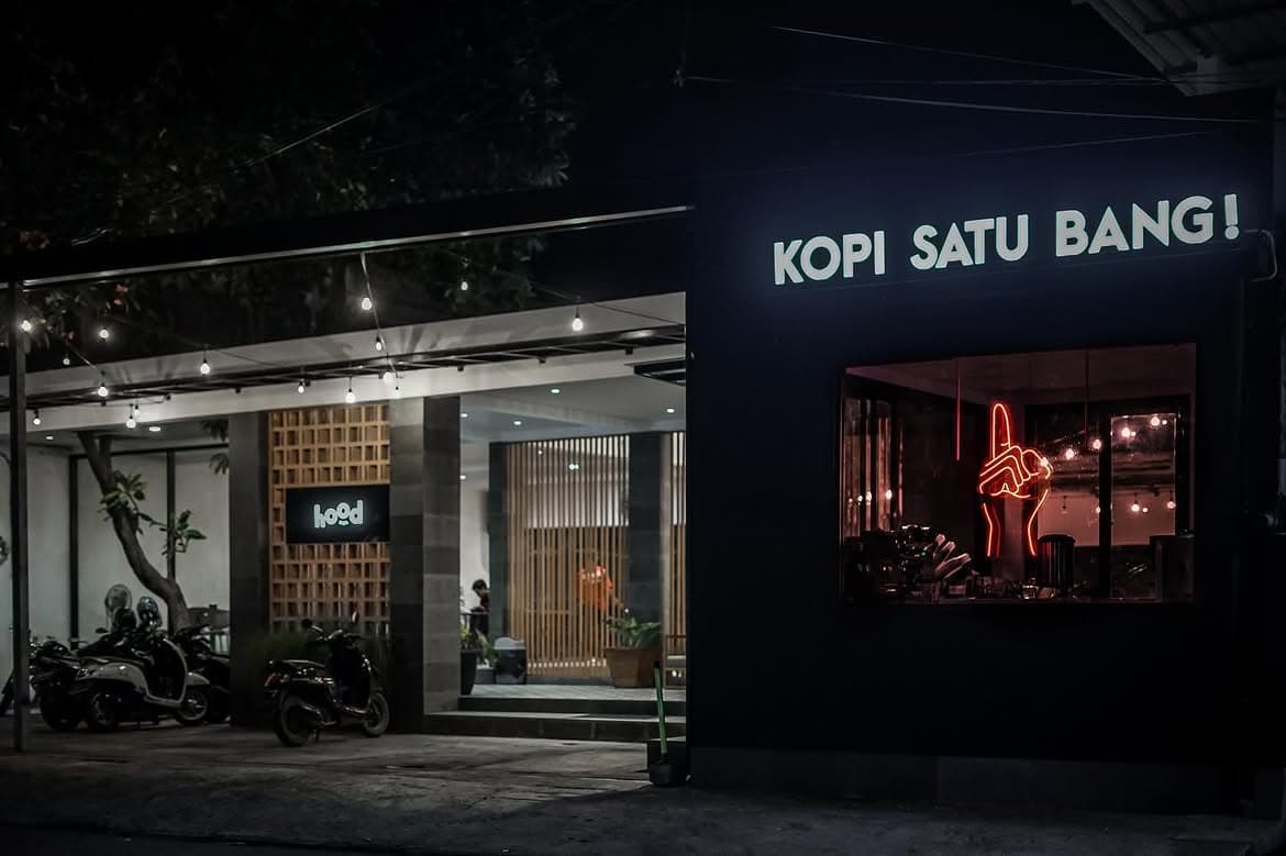 Fasad Kopi Satu Bang pada malam hari dengan papan nama dan neon merah